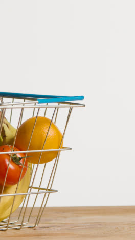 Vertical-Video-Shot-Of-Basic-Fresh-Fruit-And-Vegetable-Food-Items-In-Supermarket-Wire-Shopping-Basket-